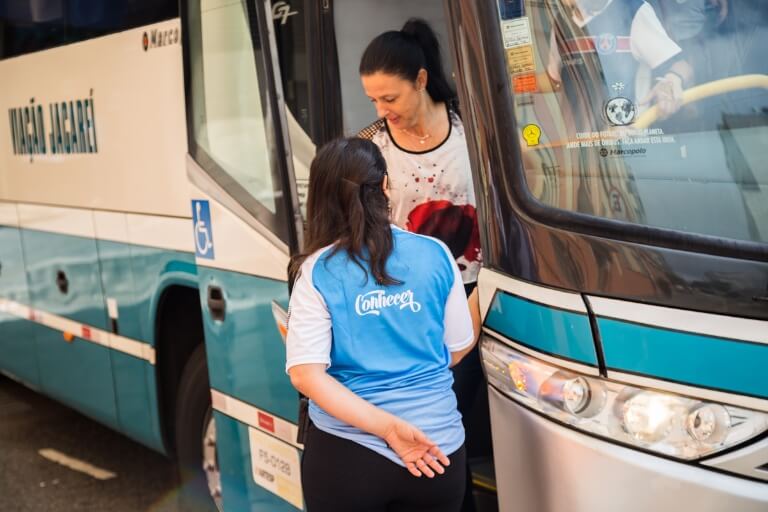 Monitora especializada auxiliando professora a descer de ônibus